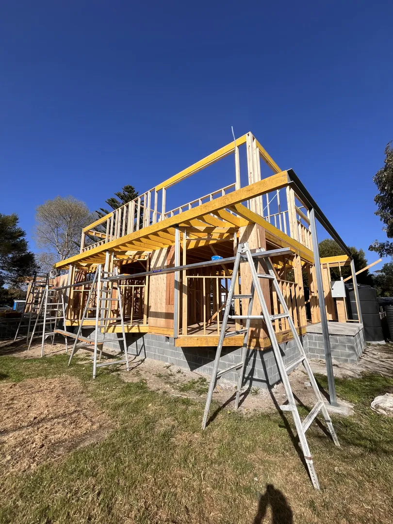 Wooden house frame under construction with blue sky.